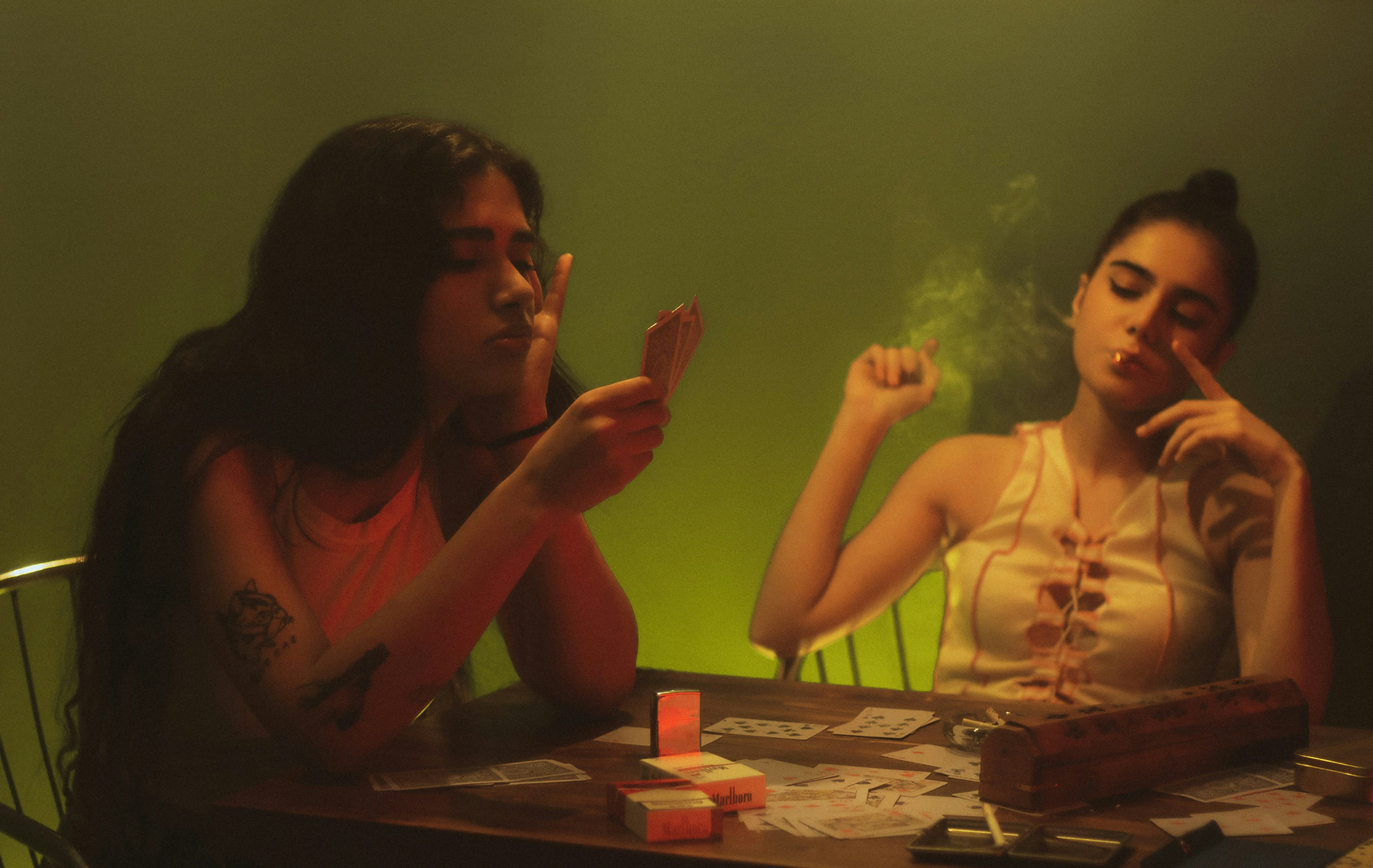 two women sitting at a table smoking cigarettes