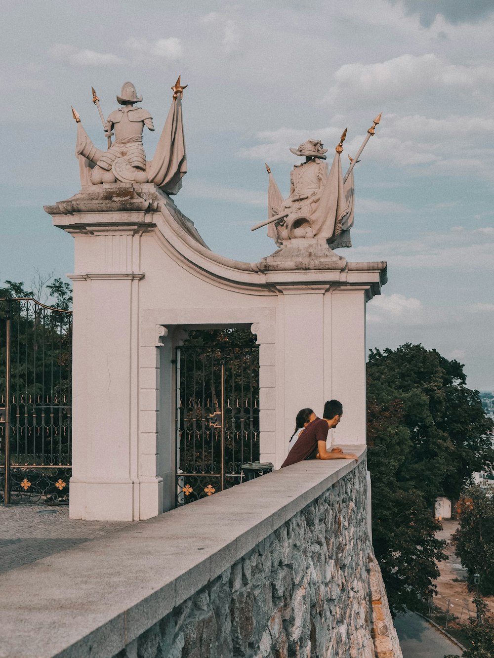 a person sitting on a wall near a gate