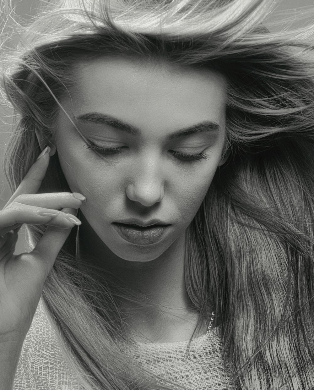 a black and white photo of a woman with her hair blowing in the wind