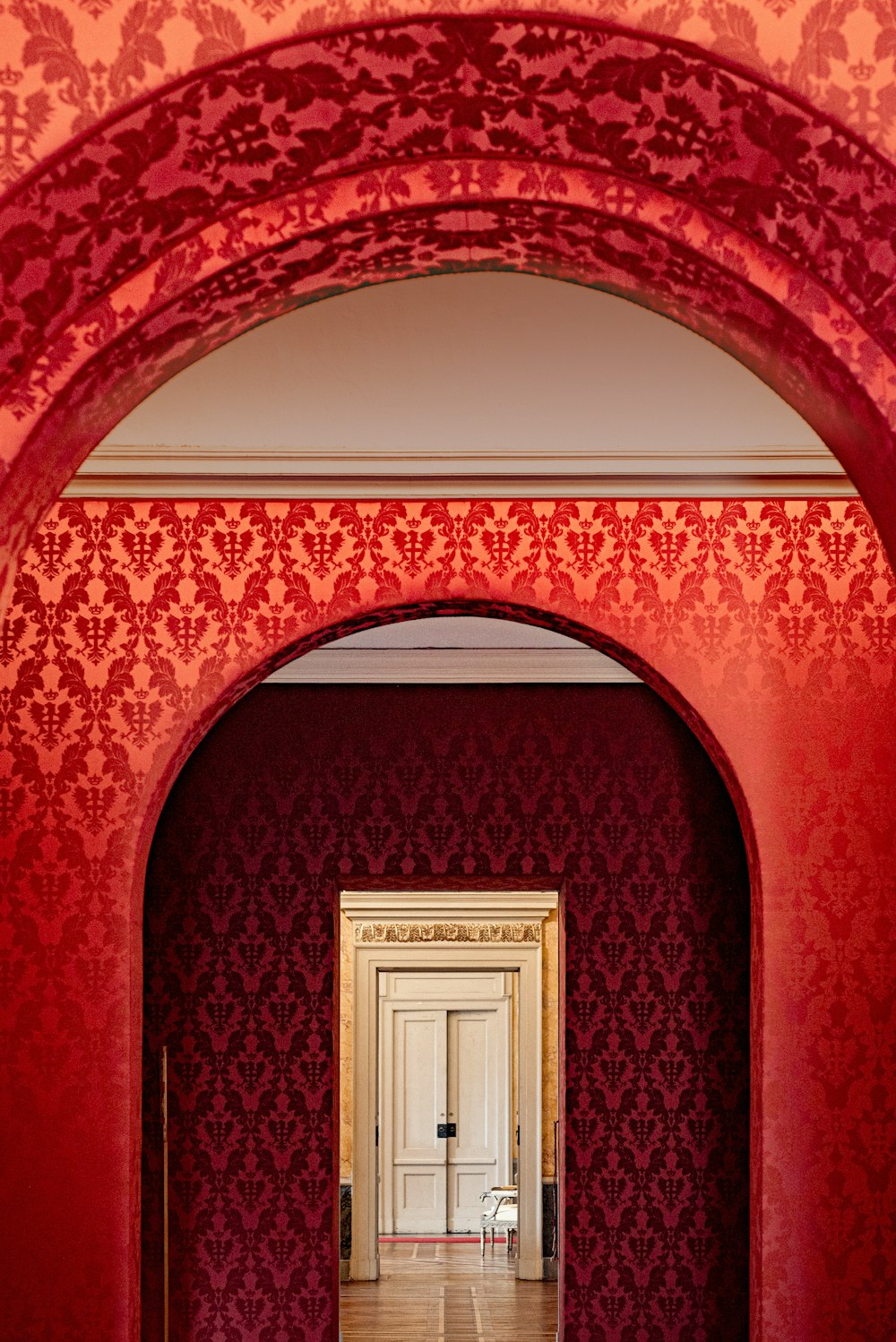 an archway leading into a room with red wallpaper