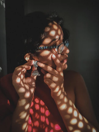 Casual daily scene of someone putting on a pair of cheerful earrings by a window.