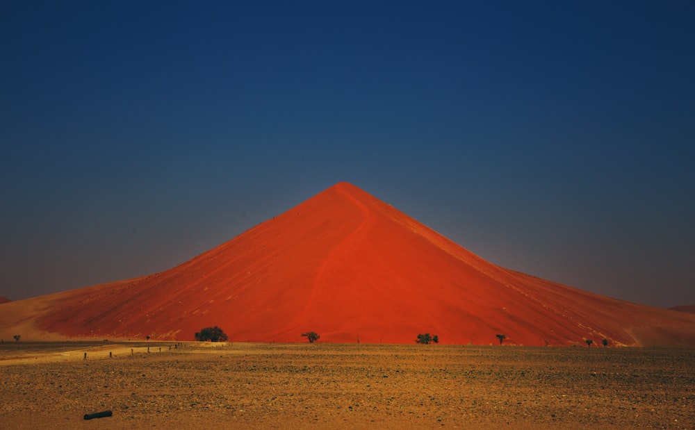 a large red mountain in the middle of a desert