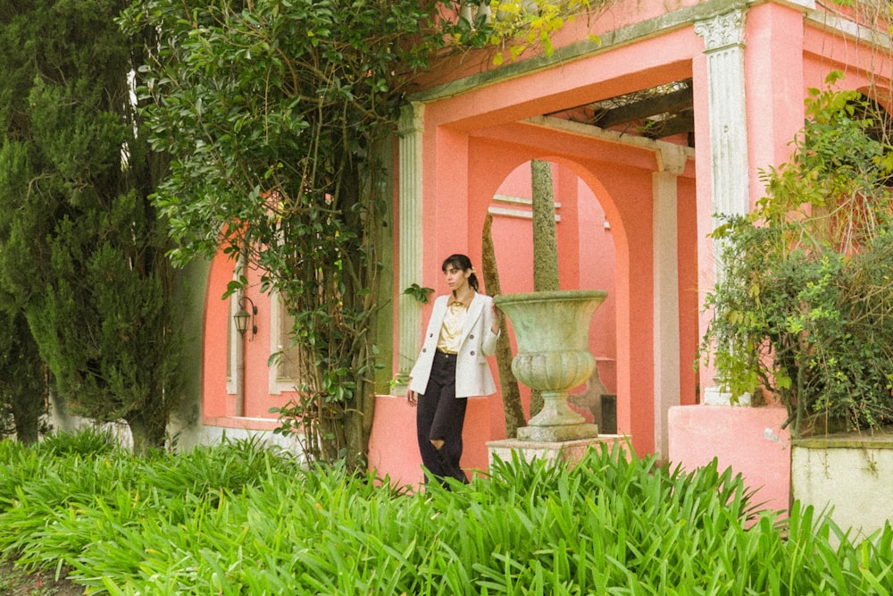 a woman standing in front of a pink building