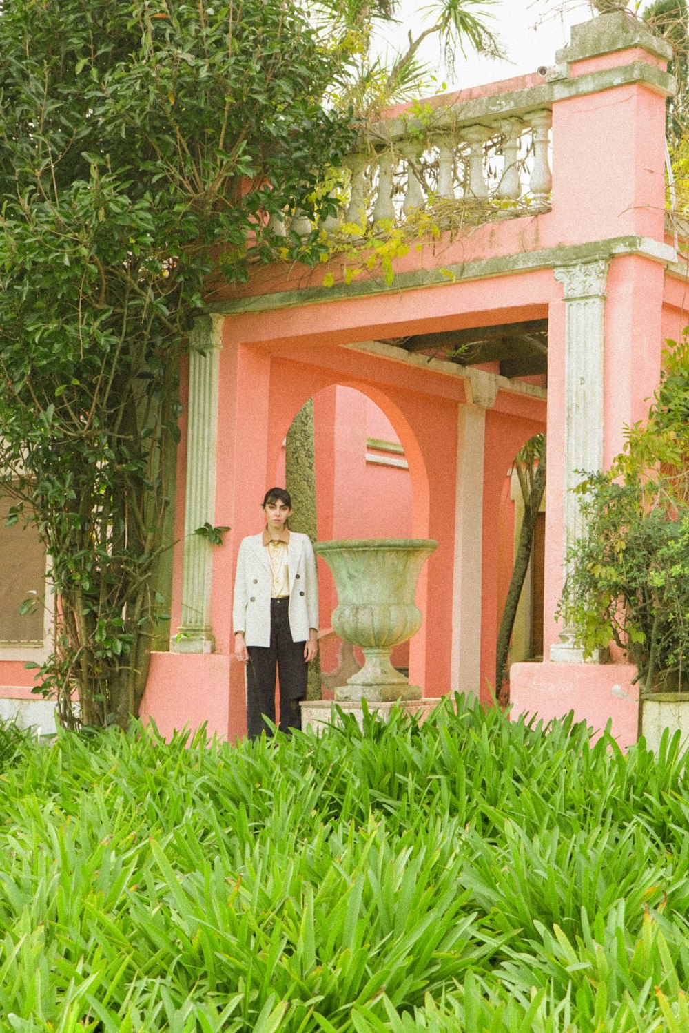 a woman standing in front of a pink building