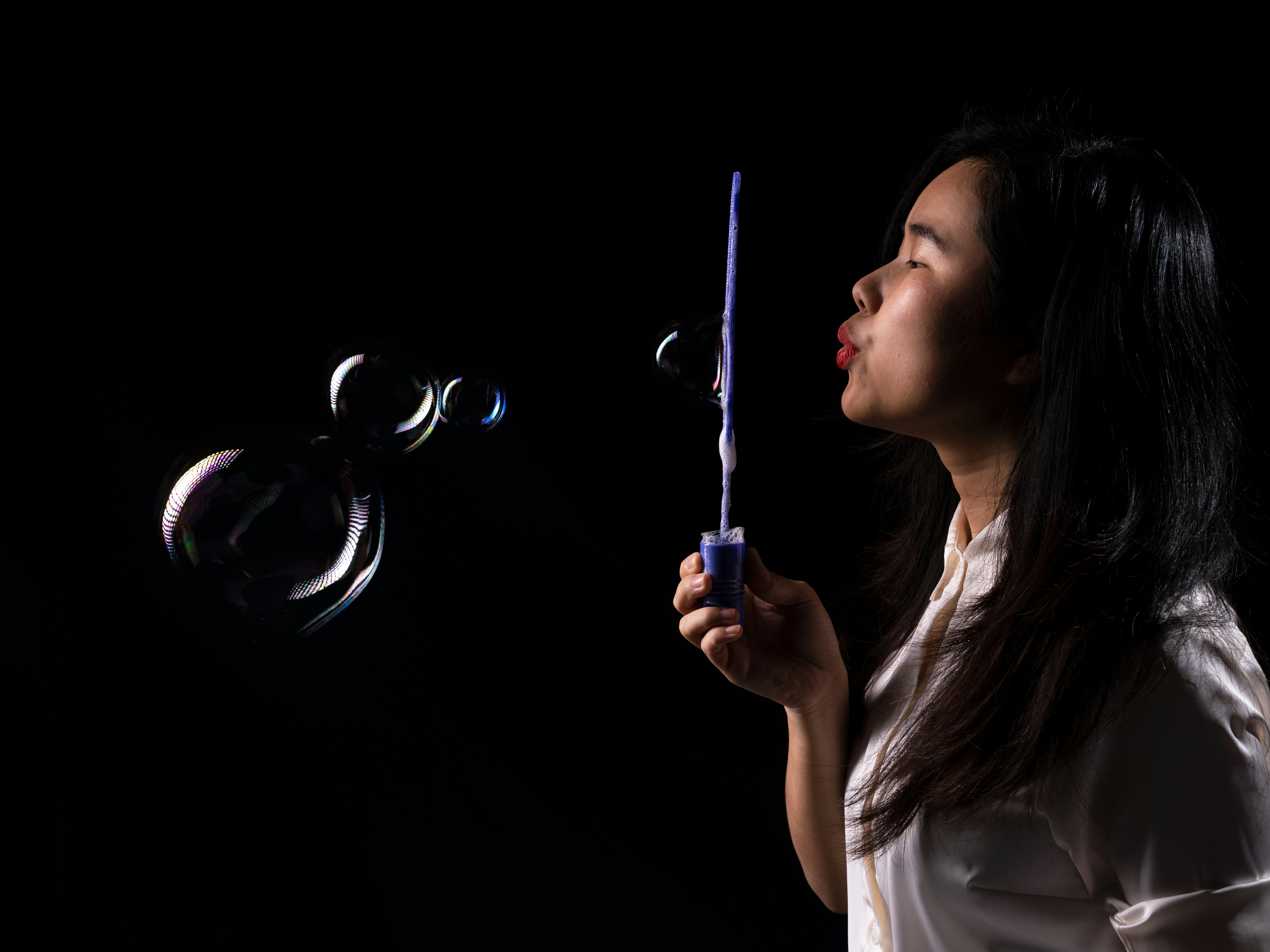 a woman blowing bubbles on a black background