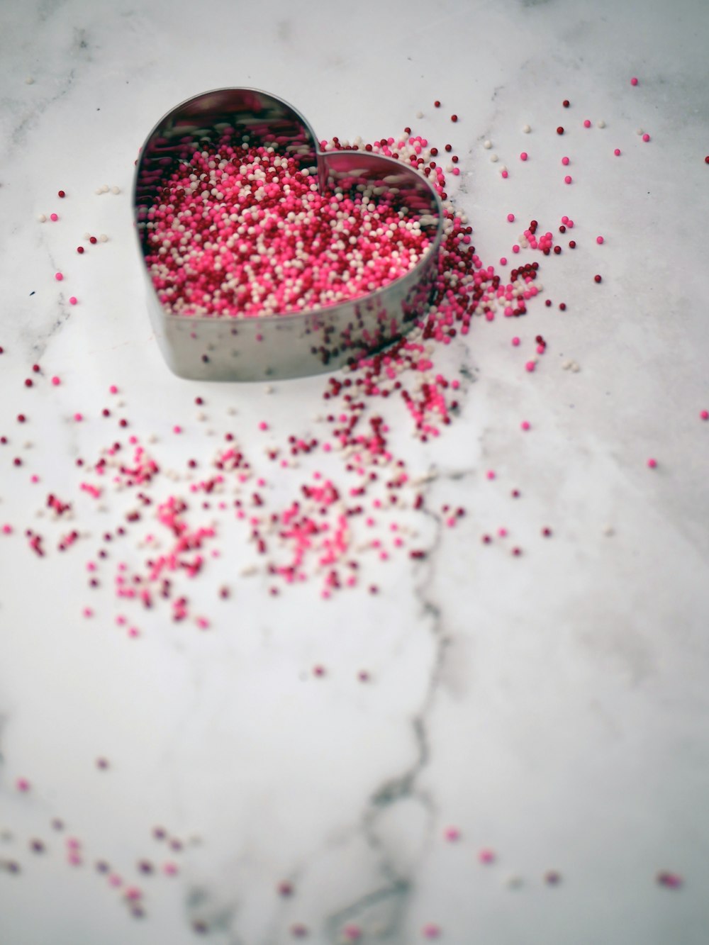 a heart shaped tin with pink sprinkles in it