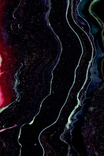 Fluid abstract painting featuring dark, sinuous lines with hints of bright colors such as red and green flowing throughout the composition. These lines create a sense of movement on the canvas, resembling an organic and otherworldly landscape.