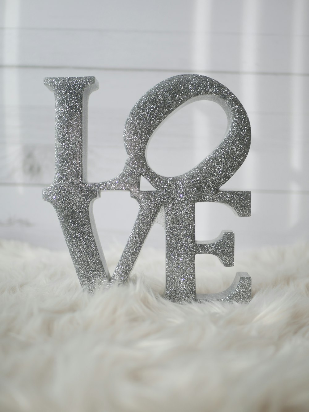 a silver love sign sitting on top of a fluffy white blanket