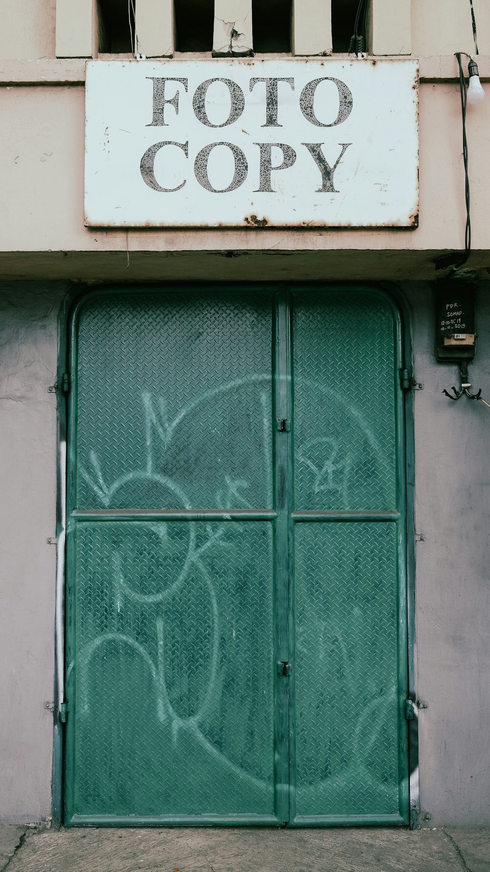 a green door with graffiti on it in front of a building