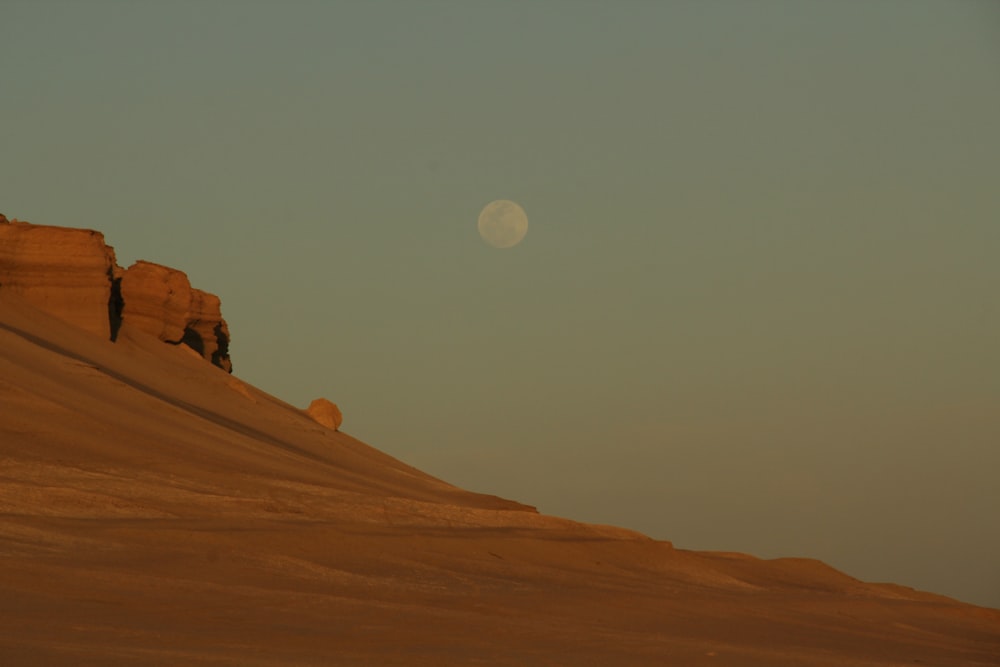 the moon is setting over a desert landscape