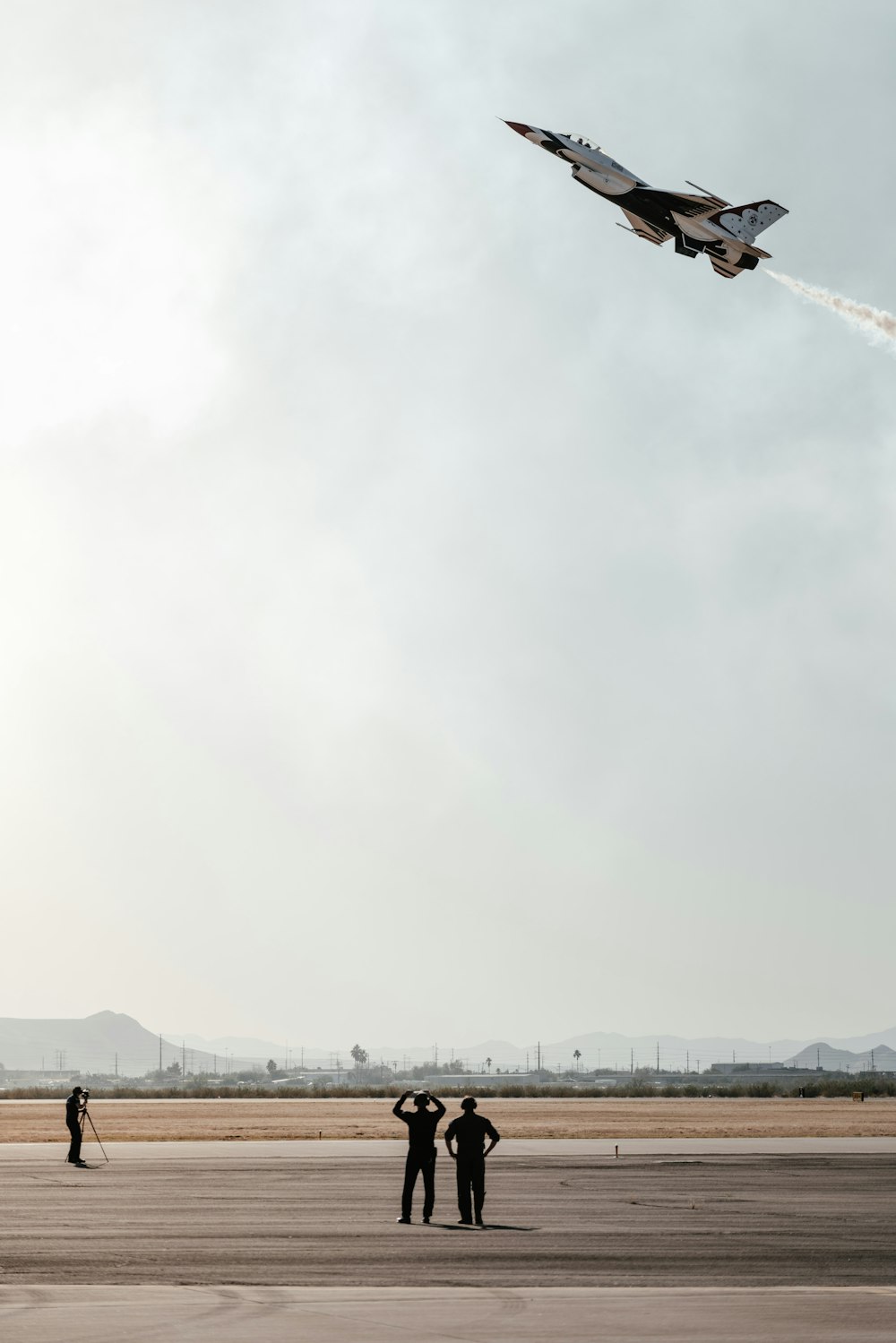 Due persone che guardano un jet da combattimento volare nel cielo
