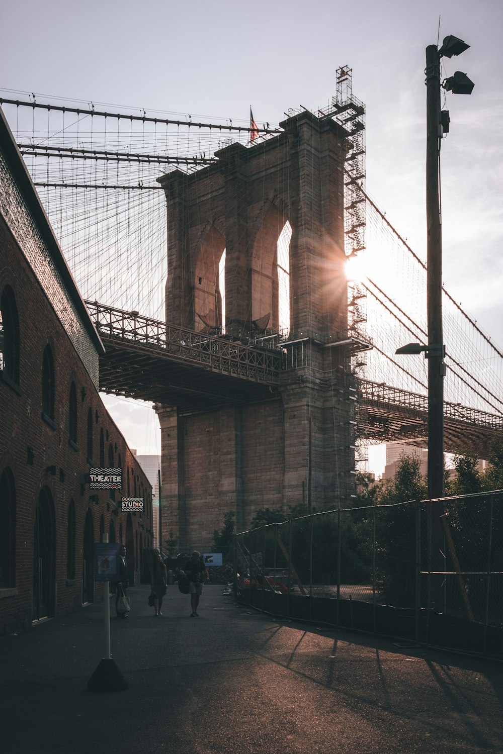 people walking on a sidewalk near a bridge