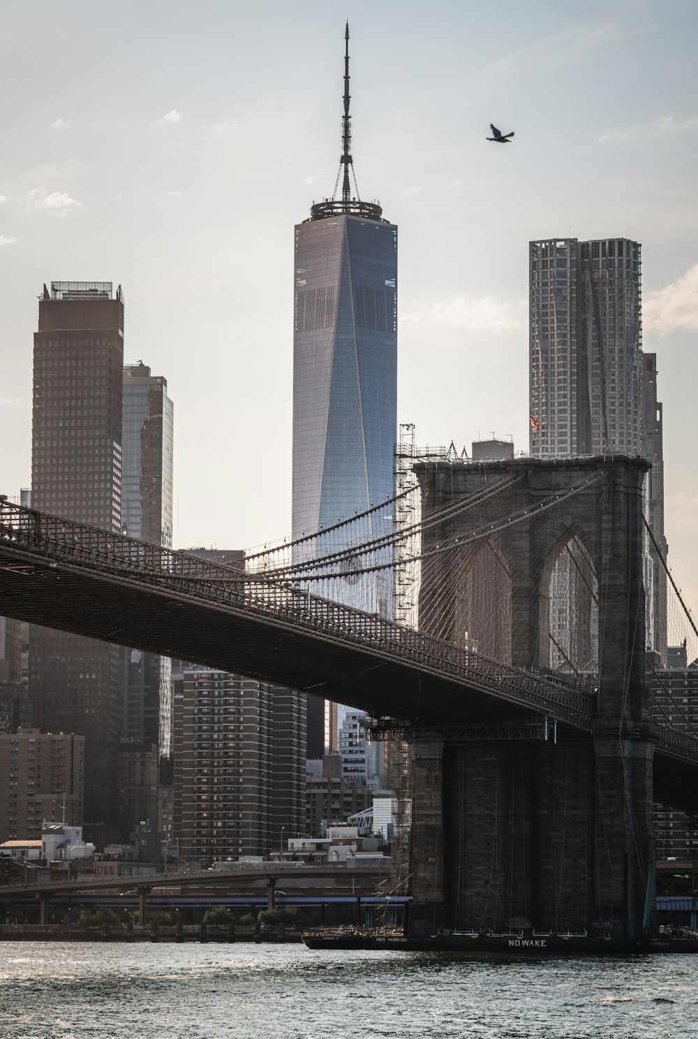 an airplane flying over a bridge with a city in the background