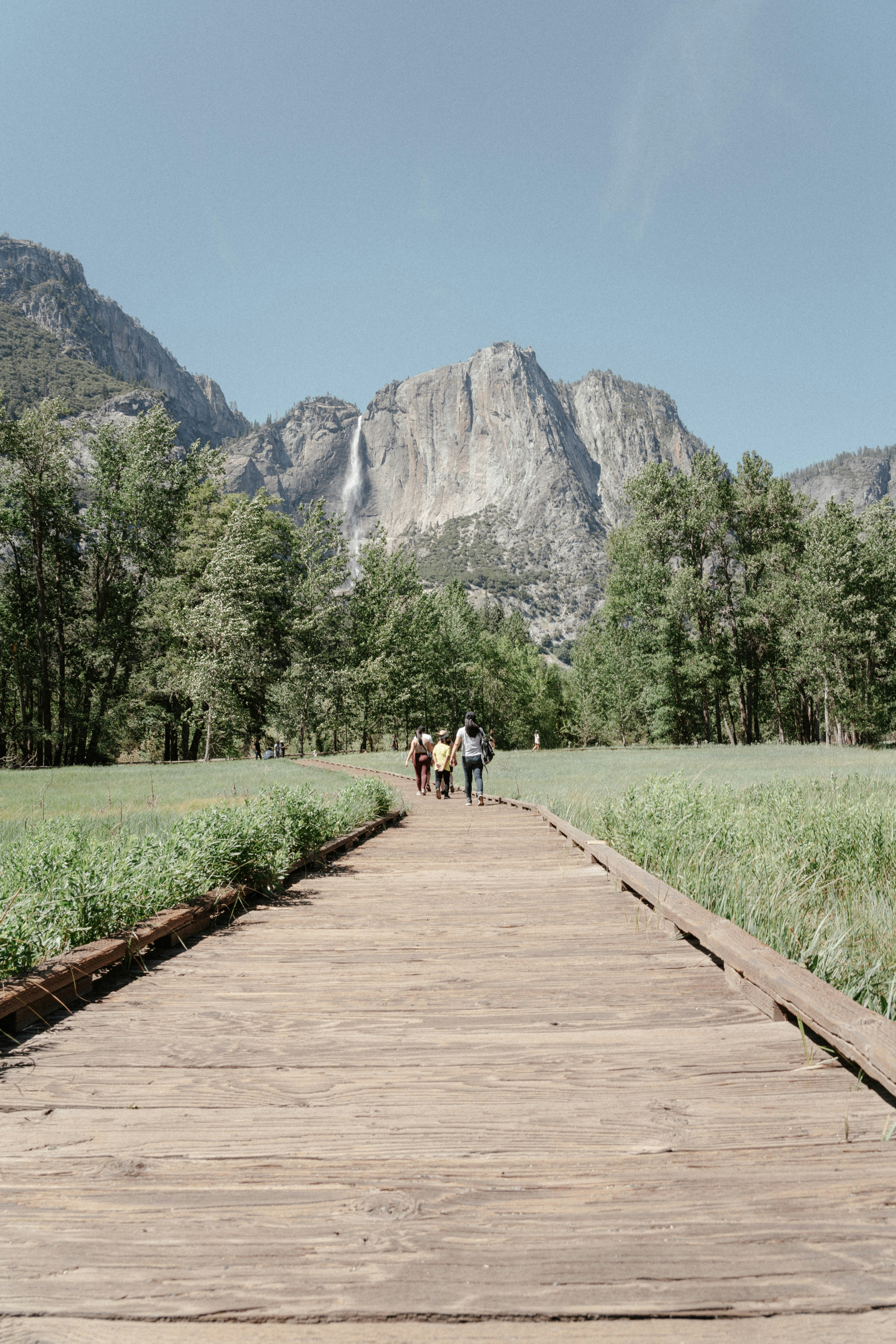 Three people walking down a wooden path in the mountains photo – Free ...