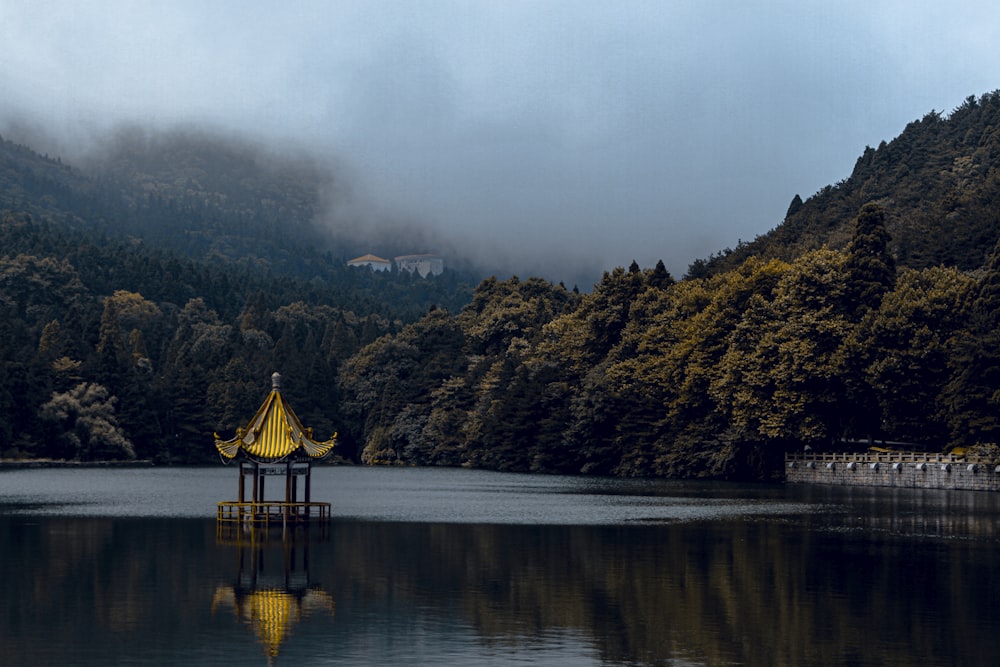 a gazebo in the middle of a lake surrounded by mountains