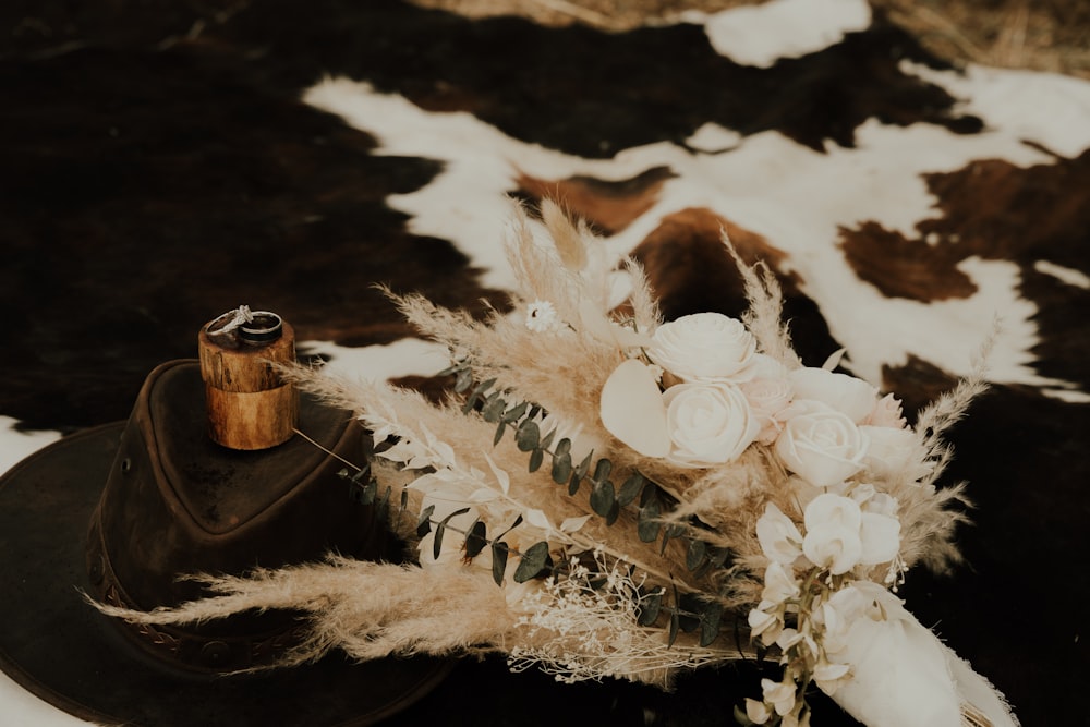 a hat and a bouquet of flowers on a cow hide