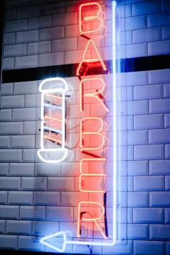 Blue neon flex sign shaped as a stylish barber pole glowing brightly in a trendy barber shop.