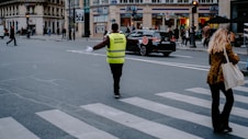 a man in a yellow vest crossing a street