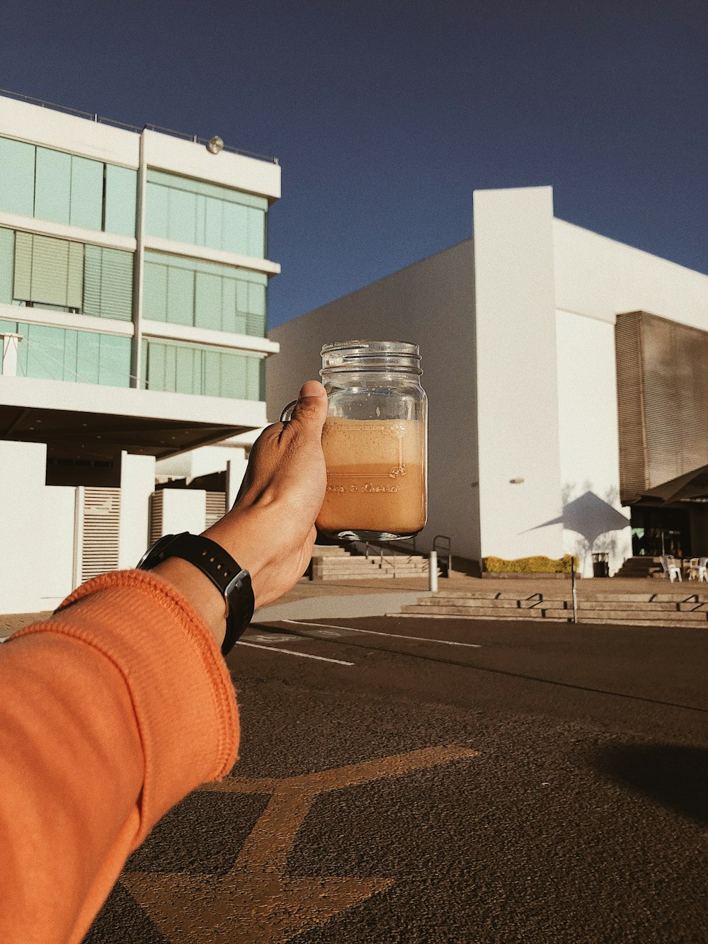 a person holding a jar of liquid in front of a building