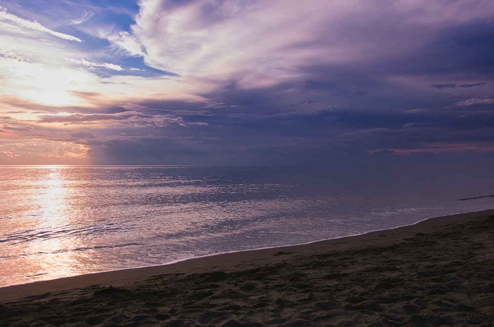 the sun is setting over the ocean on the beach