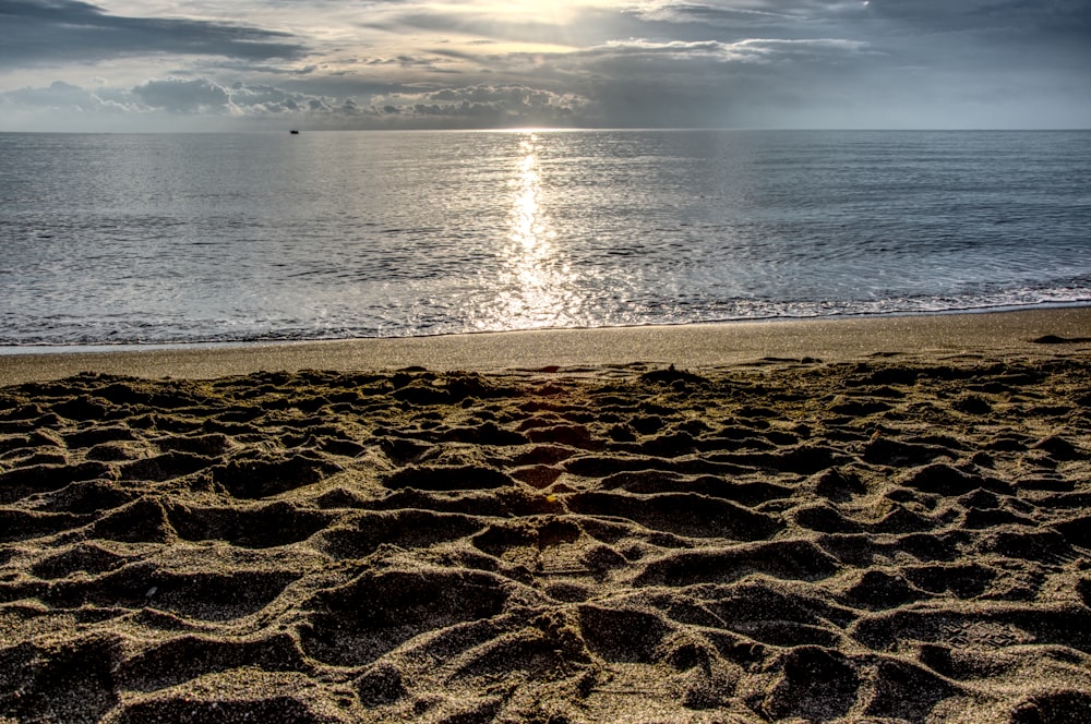 the sun is shining over the ocean on the beach