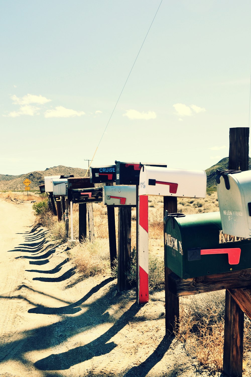 a row of mail boxes sitting on the side of a dirt road