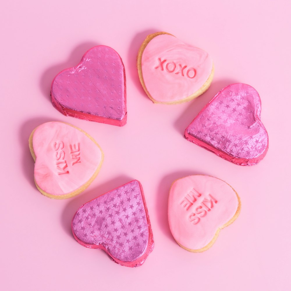 a group of heart shaped cookies sitting on top of a pink table