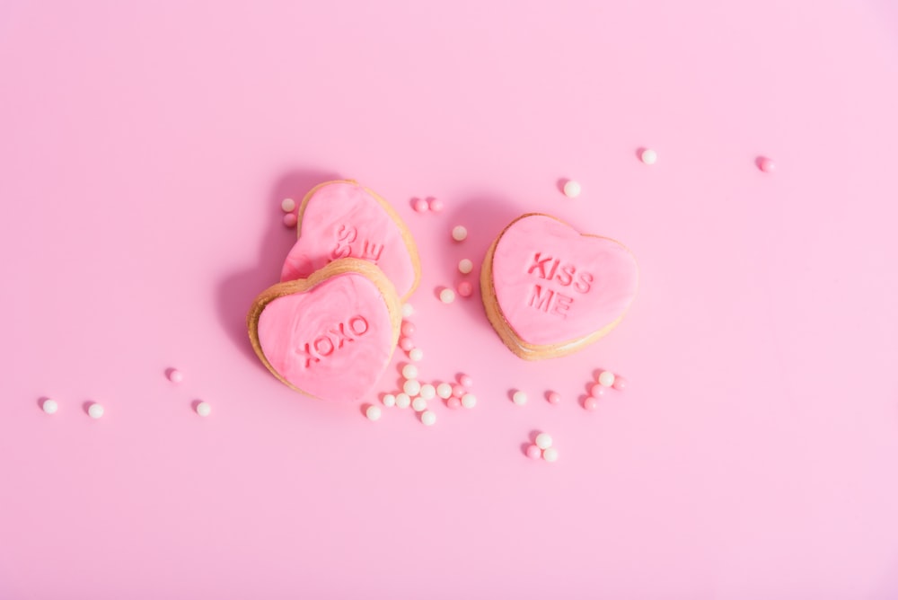 two heart shaped cookies on a pink background