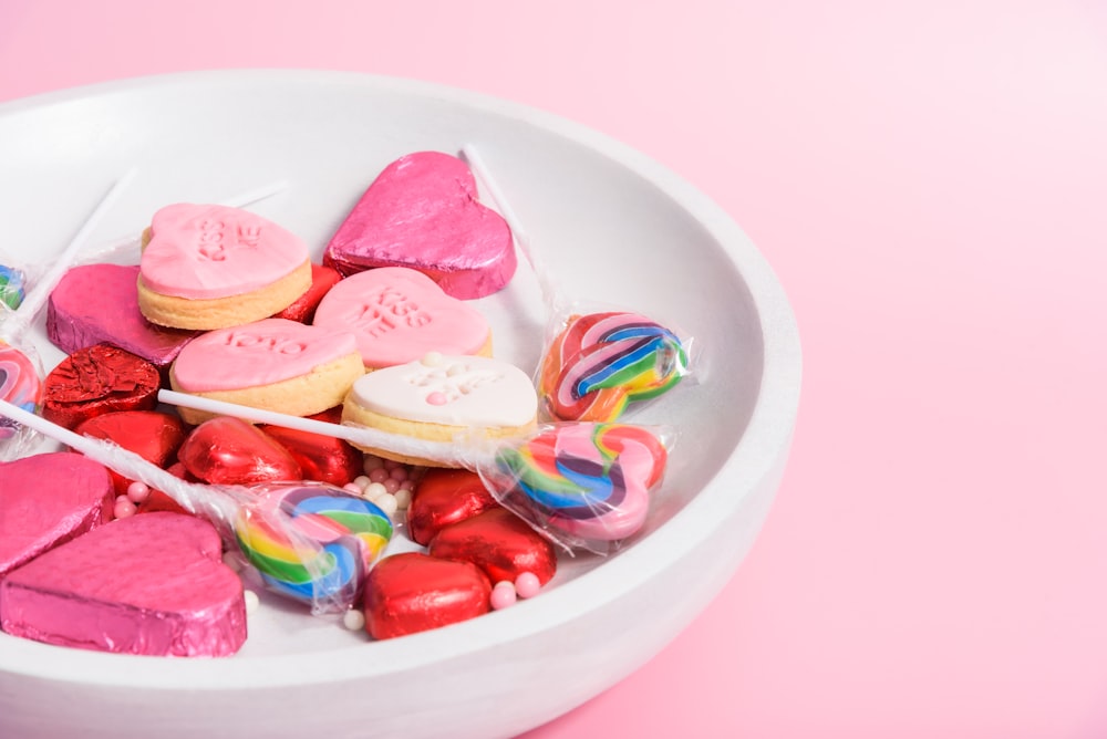 a white bowl filled with lots of heart shaped candy