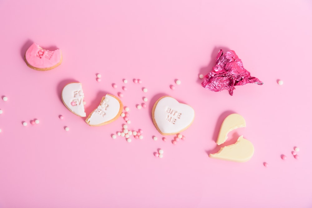 a pink background with cookies and candies in the shape of hearts