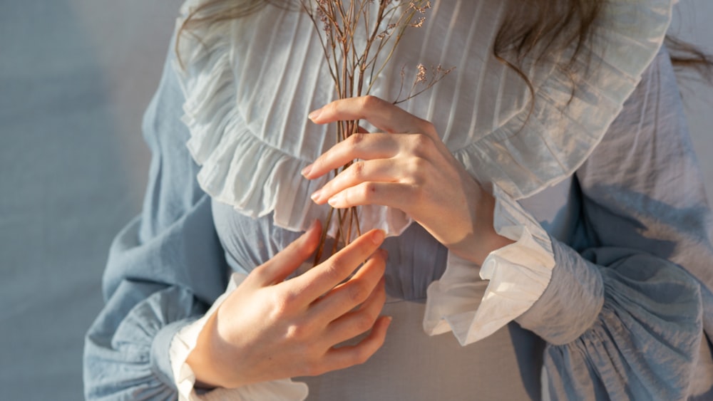 a woman holding a bunch of flowers in her hands