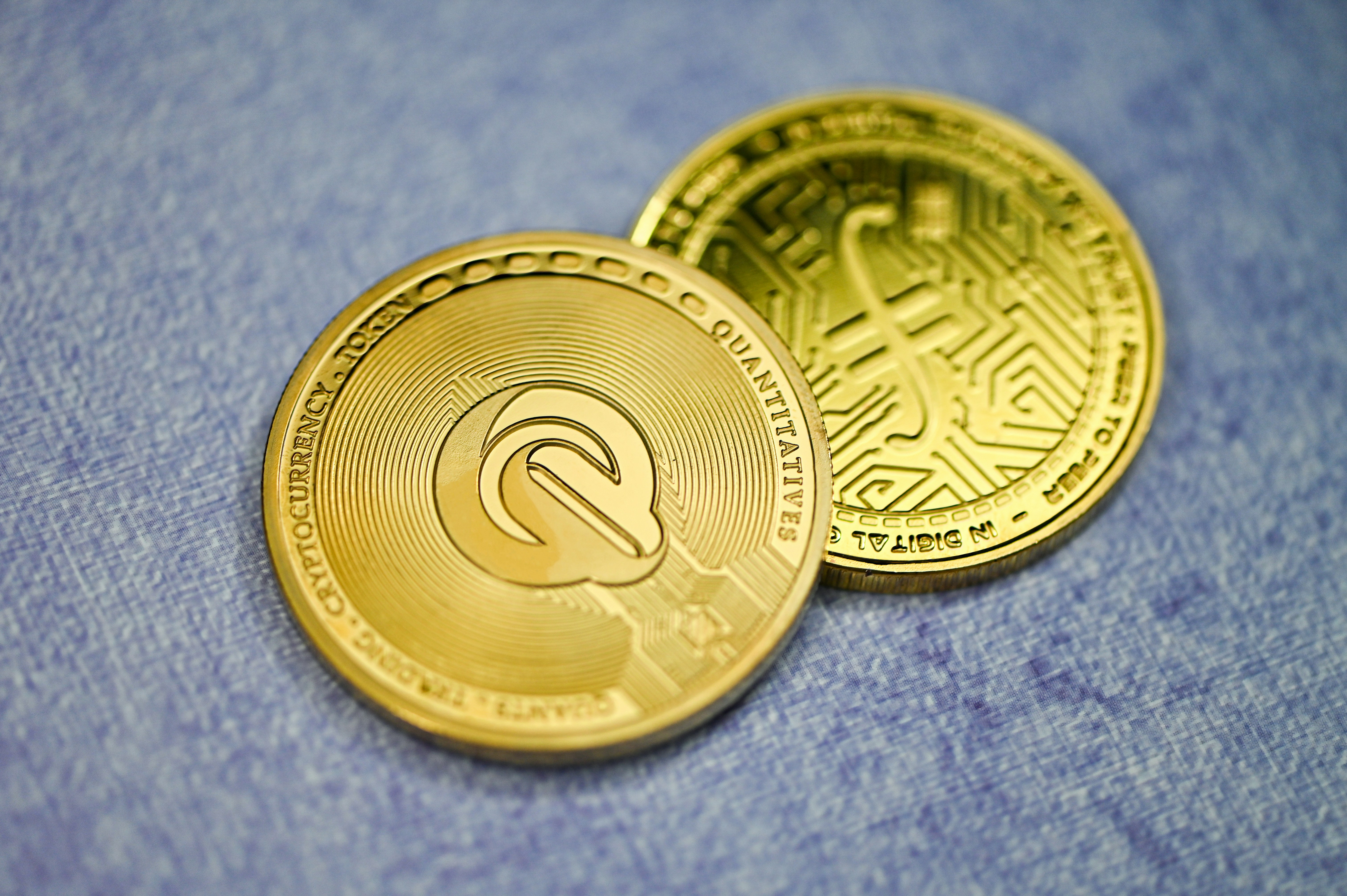 QEST coin and Filecoin placed on a blue background