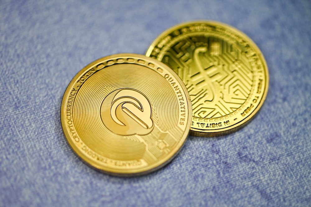 two gold coin sitting on top of a blue cloth