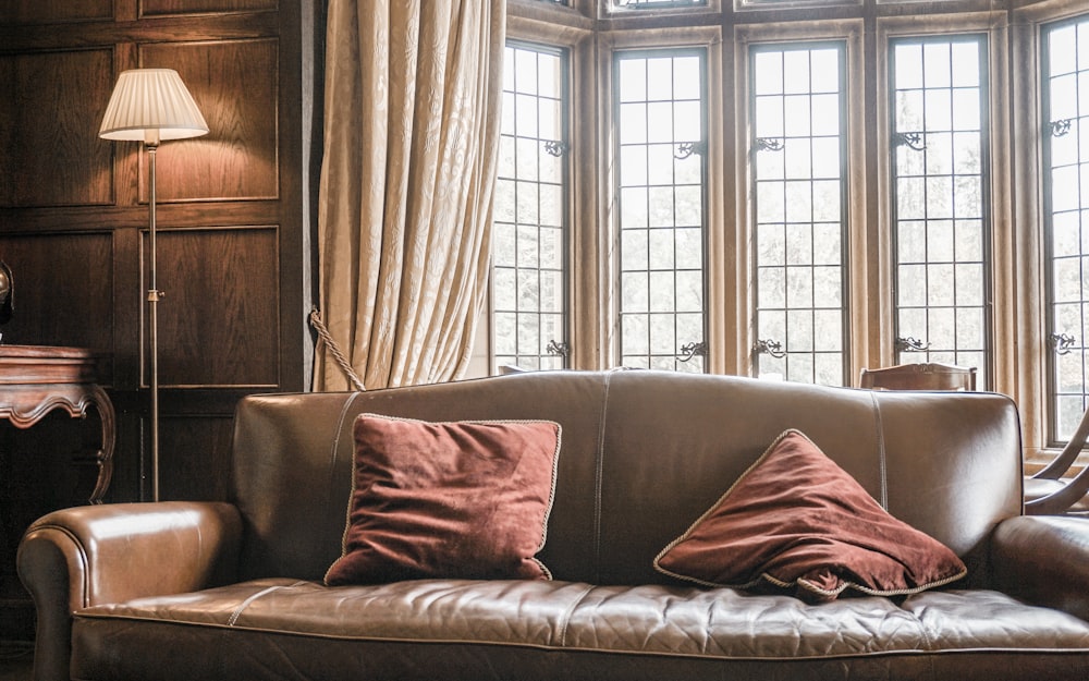 a brown leather couch sitting in front of a window