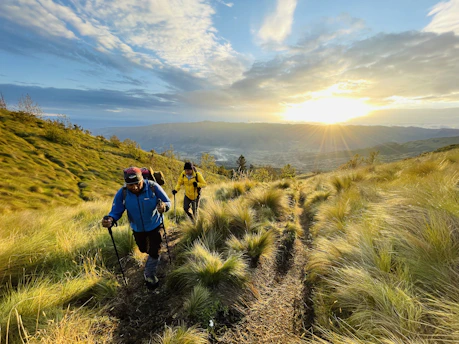 A hiker walking along a mountain trail wearing the sleek hypershell exoskeleton at sunset