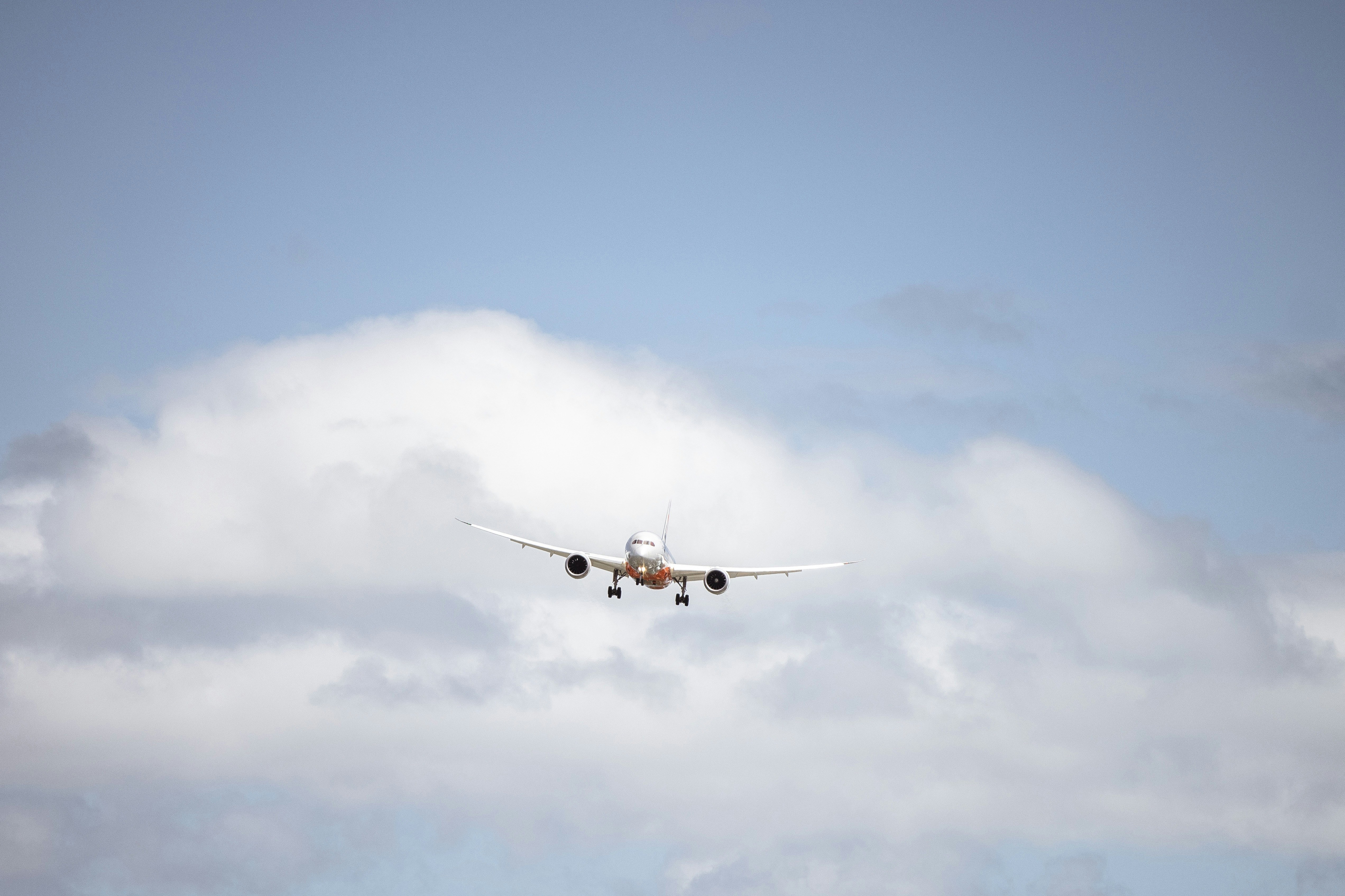 an airplane flying in the sky with a cloud in the background, Gold Coast Airport by Josh Withers