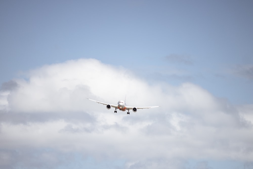 an airplane flying in the sky with a cloud in the background