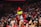 a mascot in a red and white outfit standing in front of a crowd
