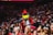 a mascot in a red and white outfit standing in front of a crowd