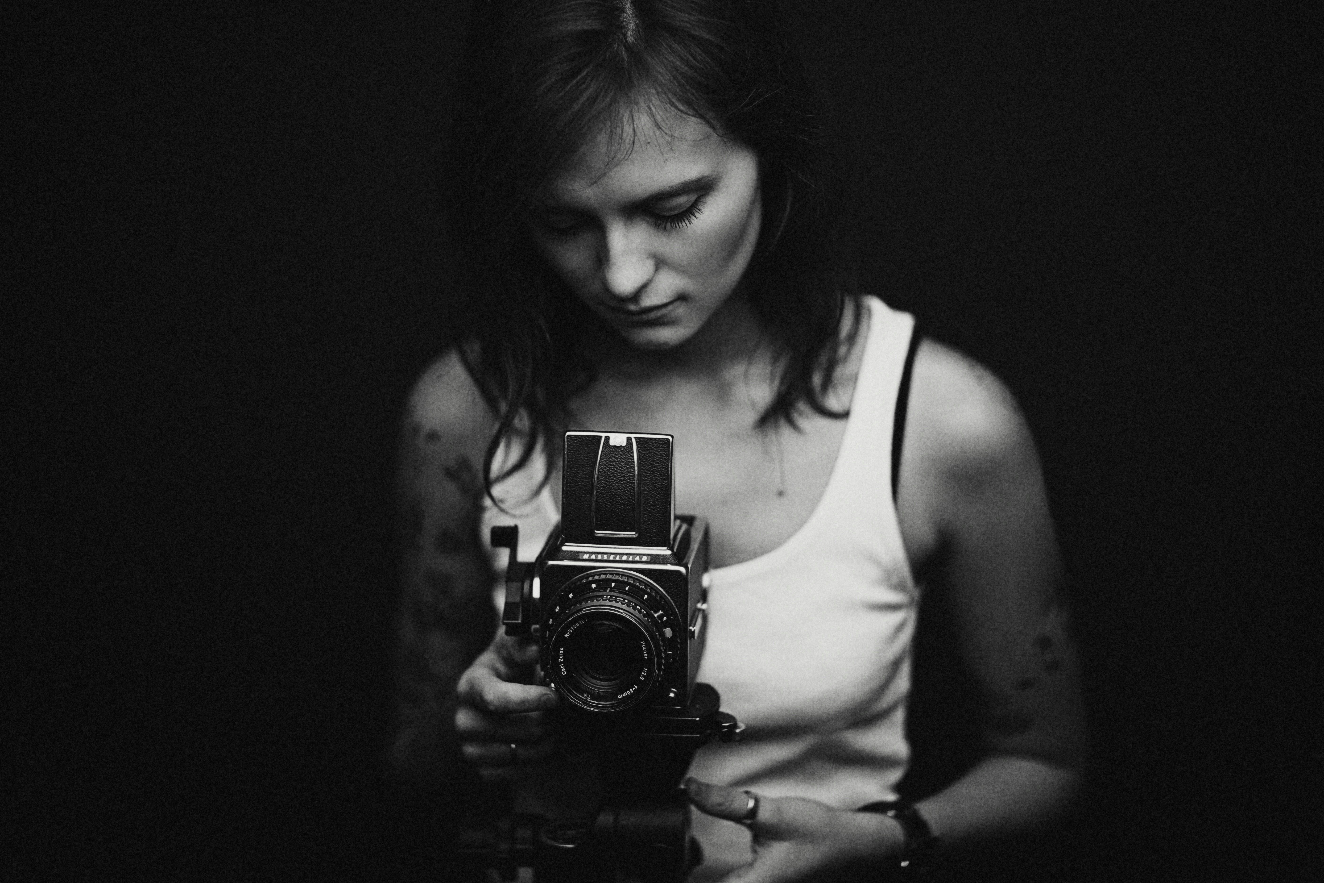 Black and white portrait of a photographer looking down into a medium-format camera