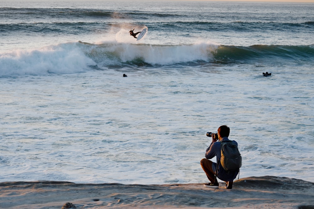 a man taking a picture of a surfer in the ocean