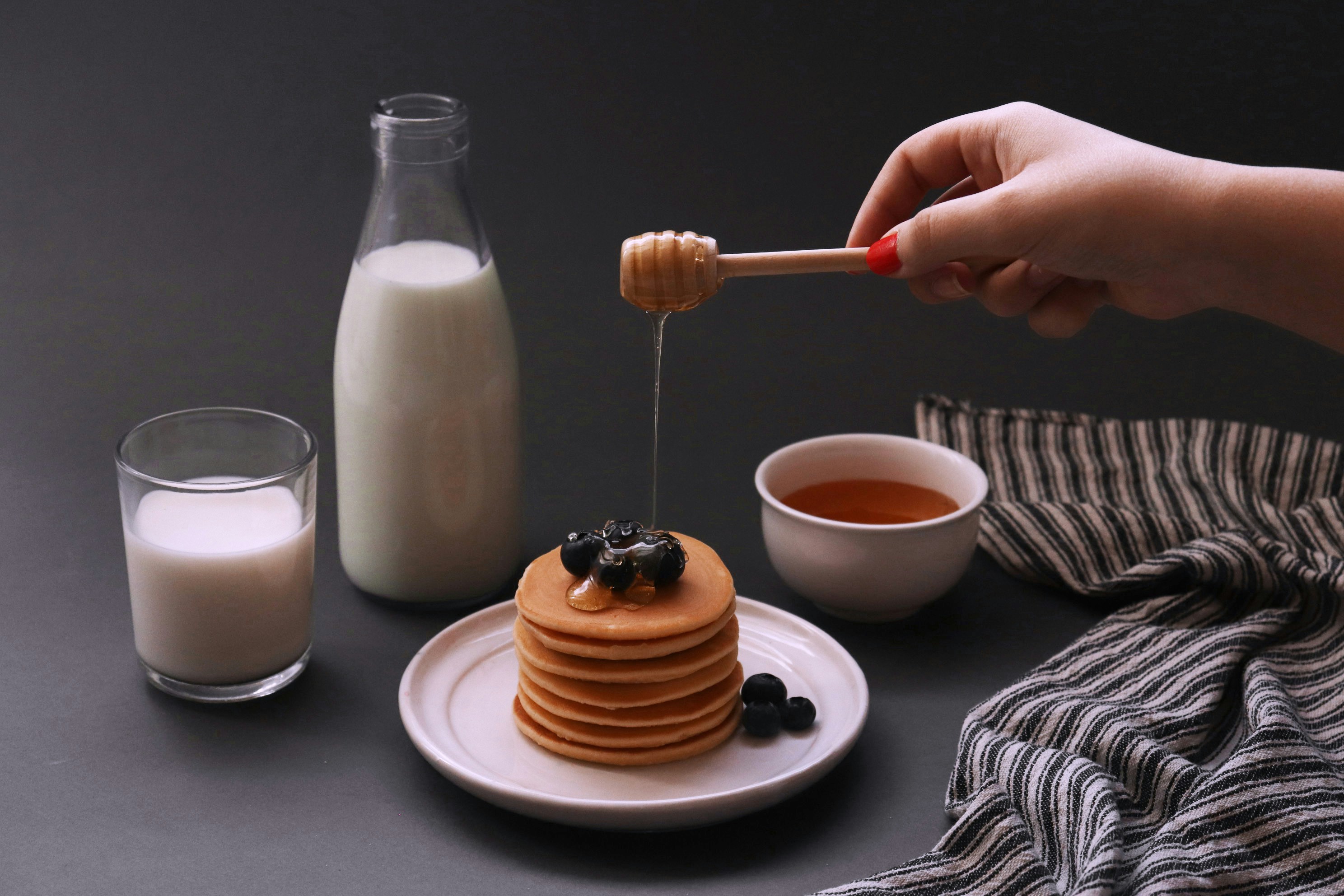 a stack of pancakes on a plate with syrup and a glass of milk