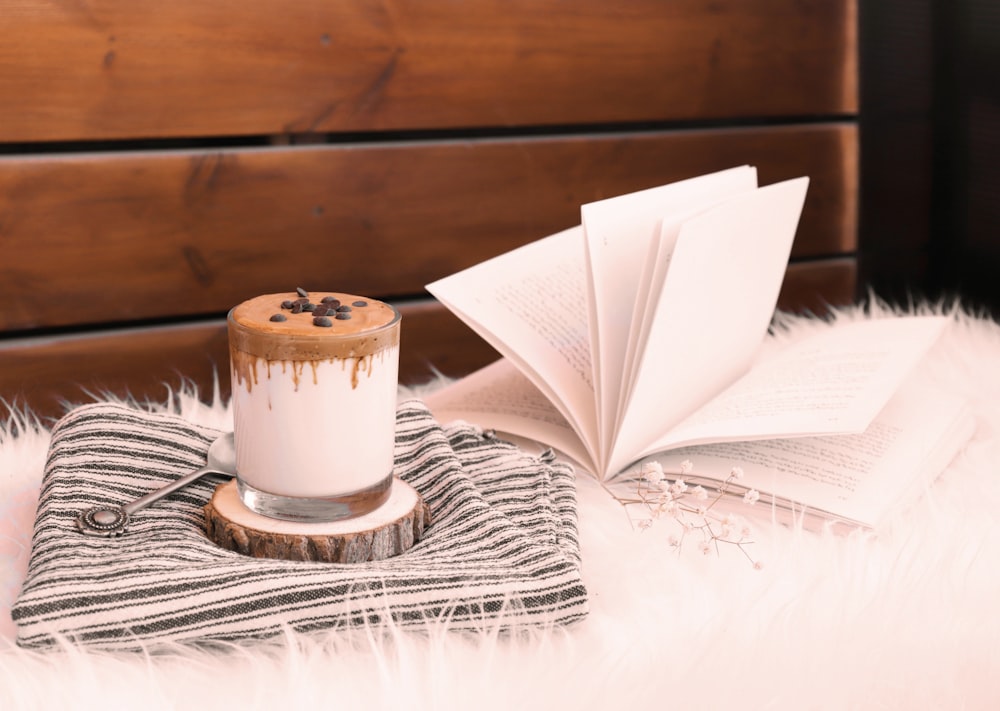 a cup of coffee sitting on top of a blanket next to an open book