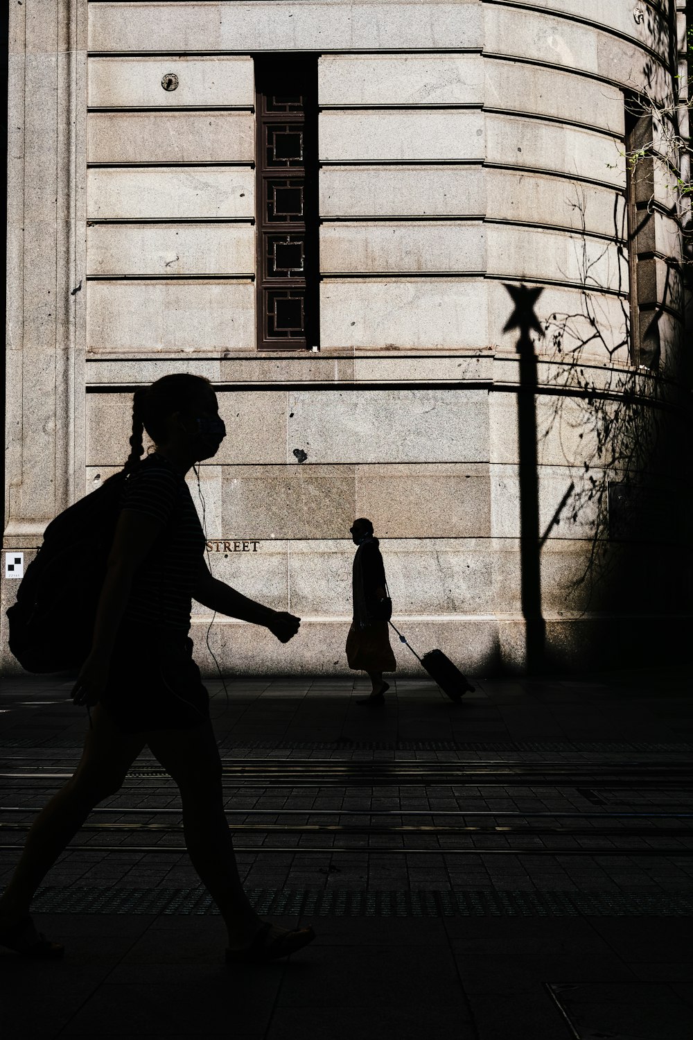 a woman walking down a street past a tall building