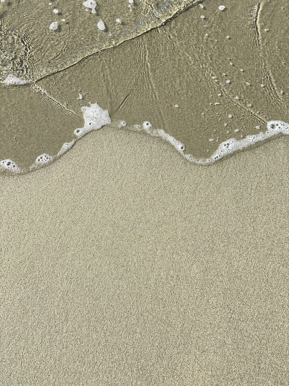 a sandy beach with waves coming in to shore