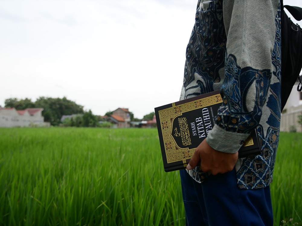 a person standing in a field holding a book