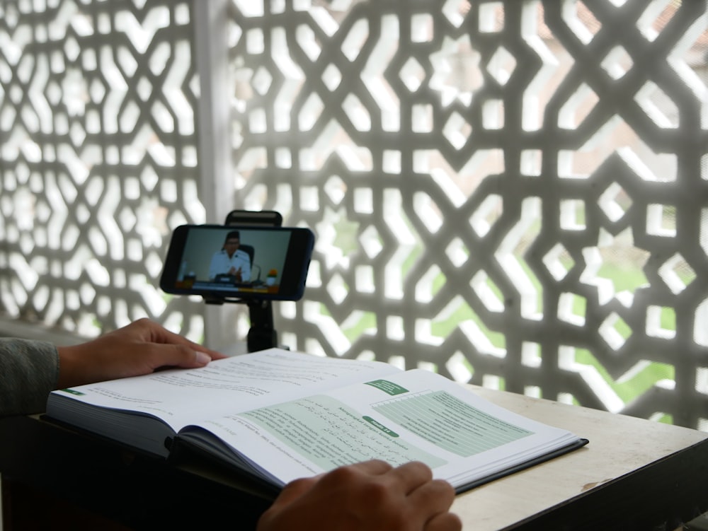 a person sitting at a desk with a book and a cell phone