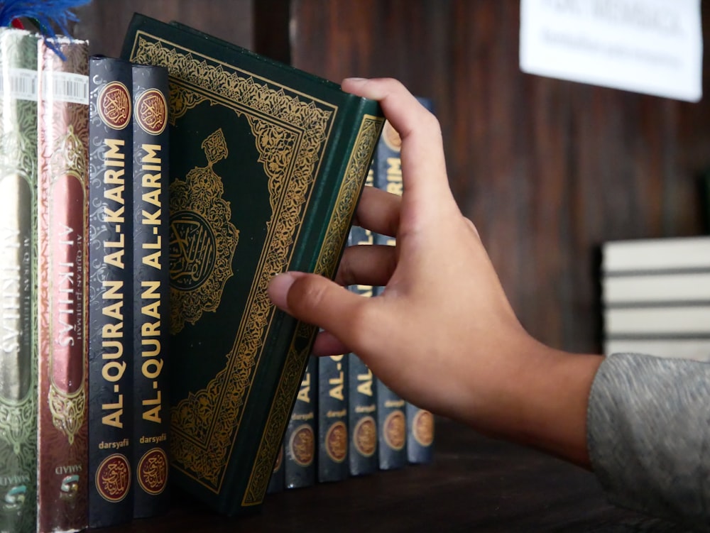 a person holding a book in front of a stack of books