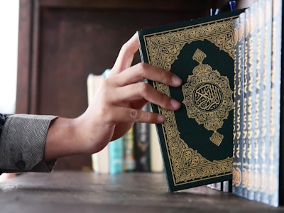a person holding a book in front of a bookshelf