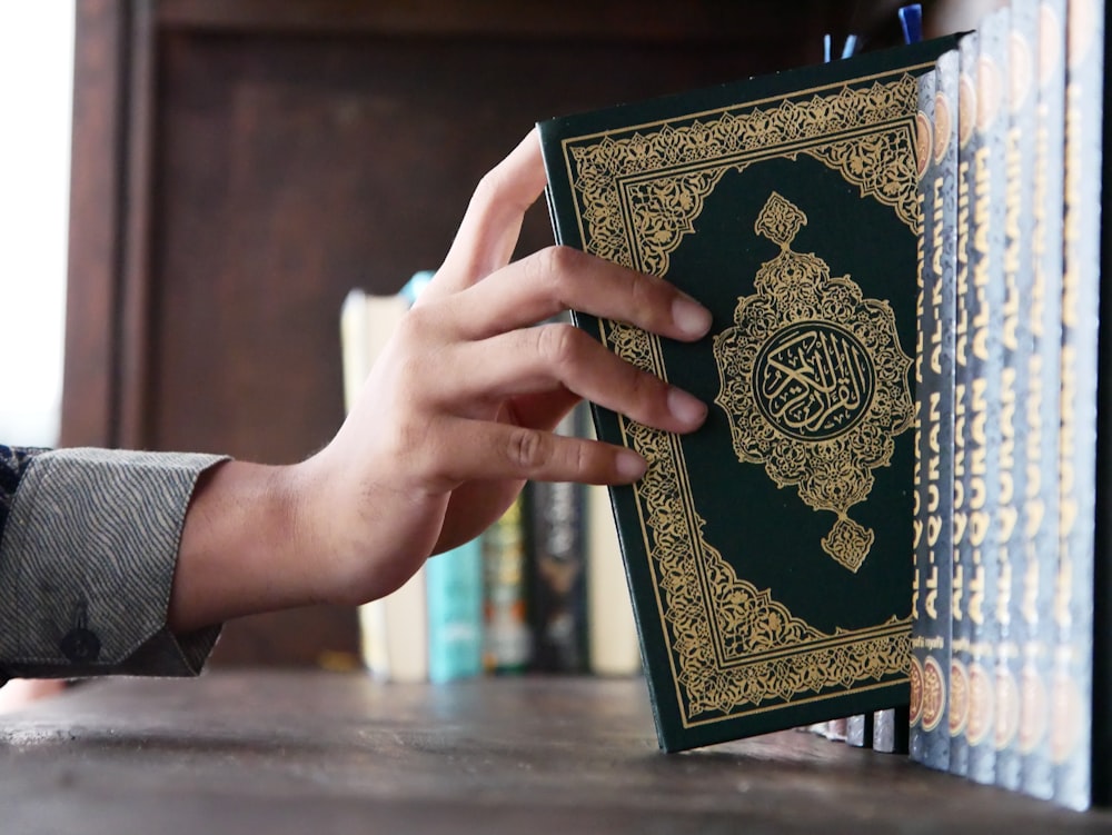 a person holding a book in front of a bookshelf